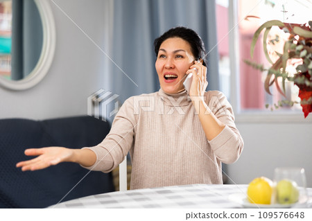 Positive asian woman communicates with someone on mobile phone Positive asian woman communicates with someone on mobile phone 109576648