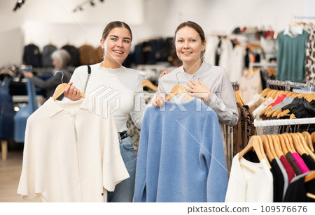 Young and adult women choosing coat in store Young and adult women choosing coat in store 109576676