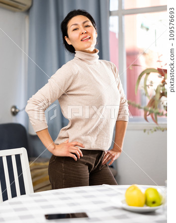 Smiling woman posing at table in living room 109576693