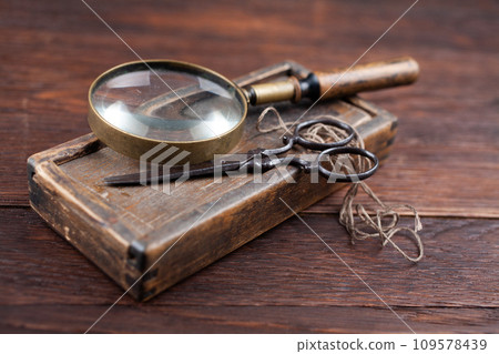 Antique accessories wooden box, old vintage retro scissors and magnifying glass. Antique accessories wooden box, old vintage retro scissors and magnifying glass. 109578439