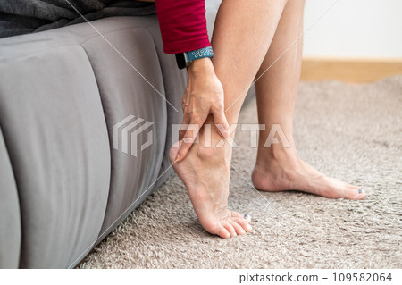 Foot pain, Asian woman sitting feeling foot pain at home, woman suffering from foot pain using hand massage to relax muscles from soles of feet Foot pain, Asian woman sitting feeling foot pain at home, woman suffering from foot pain using hand massage to relax muscles from soles of feet 109582064