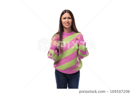 upset young brunette woman in a striped pink sweater on a white background with copy space upset young brunette woman in a striped pink sweater on a white background with copy space 109587206