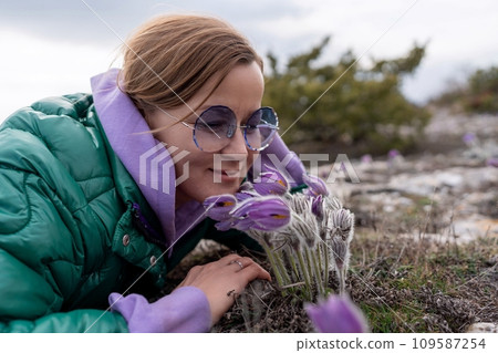Dream grass woman spring flower. Woman lies on the ground and hugs flowers pasqueflower or Pulsatilla Grandis flowers 109587254