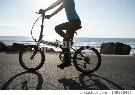 Riding folding bike on sunrise seaside road Riding folding bike on sunrise seaside road 109588421