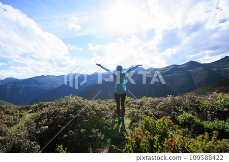 Successful woman outstretched limbs at high altitude mountain peak Successful woman outstretched limbs at high altitude mountain peak 109588422