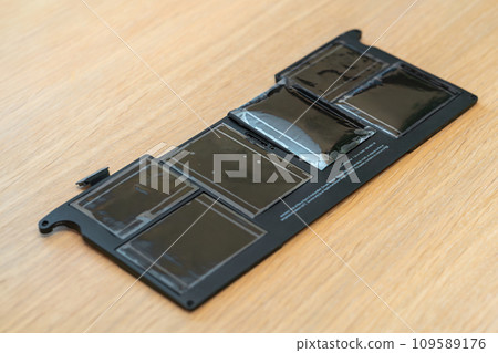 Swollen battery of broken laptop on wooden table closeup 109589176