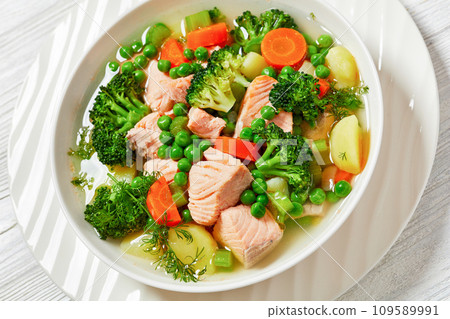 salmon, veggies and green herbs soup in bowl 109589991