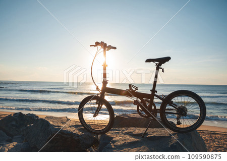 A folding bike on sunrise seaside road 109590875