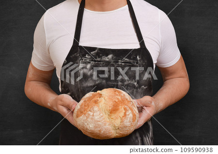 Fresh bread in the hands of a baker on a black background. Preparing cooking Fresh bread in the hands of a baker on a black background. Preparing cooking 109590938