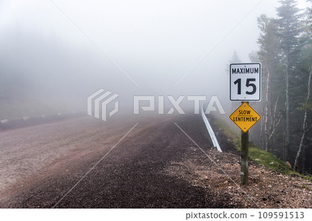 Slow Lentement sign Warning yellow roads signs road in Background foggy Cape Breton Island Nova Scotia Highlands Canada Slow Lentement sign Warning yellow roads signs road in Background foggy Cape Breton Island Nova Scotia Highlands Canada 109591513