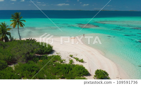 Aerial tropical island beach with coral reef crystal turquoise water. Woman back view standing in sea enjoy beautiful wild nature landscape. Yellow kayak. Summer holiday vacation Aerial tropical island beach with coral reef crystal turquoise water. Woman back view standing in sea enjoy beautiful wild nature landscape. Yellow kayak. Summer holiday vacation 109591736