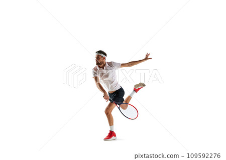 Concentered young man, tennis payer in motion during game, training, hitting ball with racket isolated over white background. Sport 109592276