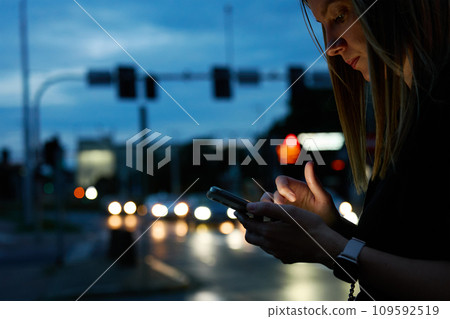 Woman using smartphone at evening street 109592519