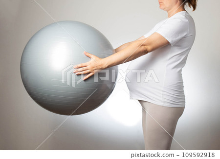 Pregnant girl with a fitball on a white background. The concept of doing sports and fitness during pregnancy. Health and pregnancy. Pregnant girl with a fitball on a white background. The concept of doing sports and fitness during pregnancy. Health and pregnancy. 109592918