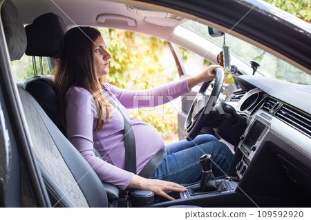A pregnant woman wearing a seat belt drives a car. Safety and driving during pregnancy. A pregnant woman wearing a seat belt drives a car. Safety and driving during pregnancy. 109592920