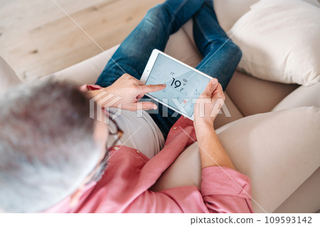 Man using smart thermostat, adjusting, lowering heating temperature at home. Concept of sustainable, efficient, and smart technology in home heating and thermostats. 109593142