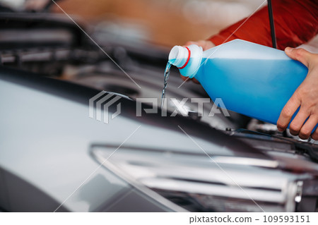 Pouring winter washer fluid into car reservoir during winter, protecting it from freezing. 109593151