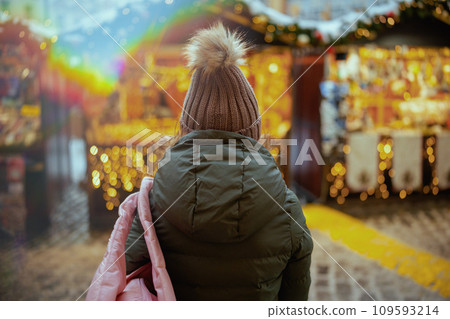 woman in green coat and brown hat at winter fair in city woman in green coat and brown hat at winter fair in city 109593214