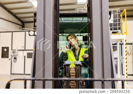 Female forklift diriver making call in warehouse. Warehouse worker preparing products for shipmennt, delivery, phone calling with manager about order. Female forklift diriver making call in warehouse. Warehouse worker preparing products for shipmennt, delivery, phone calling with manager about order. 109593238