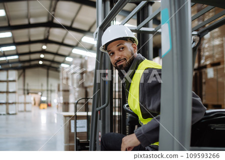 Portrait of warehouse worker driving forklift. Warehouse worker preparing products for shipmennt, delivery, checking stock in warehouse. 109593266