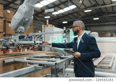 Male engineer in modern industrial factory, checking robotic arm, controling process and manufacturing equipment and machinery. Manufacturing facility with robotics and automation. 109593283