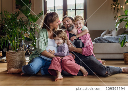 Portrait of young family at home. Pregnant mother with her children and husband in living room. Portrait of young family at home. Pregnant mother with her children and husband in living room. 109593394