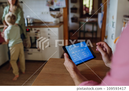 Man using smart thermostat, adjusting, lowering heating temperature at home. Concept of sustainable, efficient, and smart technology in home heating and thermostats. 109593417
