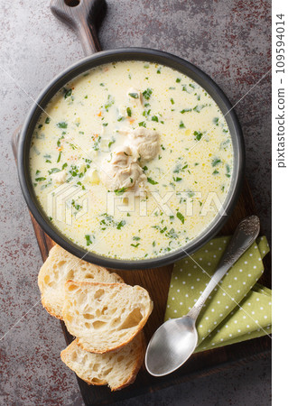 Romanian Sour Cream Garlic Chicken Soup Radauteana closeup on the plate on the table. Vertical top view 109594014