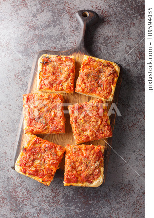 Traditional sfincione or Sicilian-style pizza with a homemade yeast crust and tomato onion sauce, cheese, and anchovies on top closeup on the wooden board. Vertical top view Traditional sfincione or Sicilian-style pizza with a homemade yeast crust and tomato onion sauce, cheese, and anchovies on top closeup on the wooden board. Vertical top view 109594035