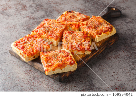 Sfincione typical oven-baked focaccia very soft and seasoned with tomato, onion, anchovies, cheese, oregano and bread crumbs closeup on the wooden board. Horizontal 109594041