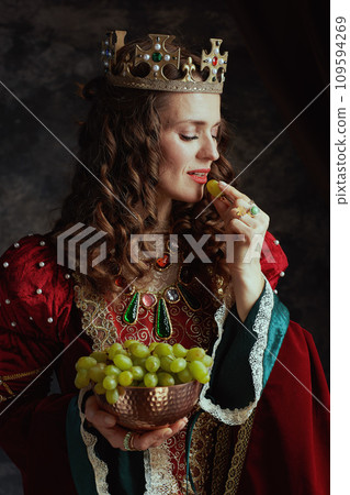 smiling medieval queen in red dress with plate of grapes smiling medieval queen in red dress with plate of grapes 109594269