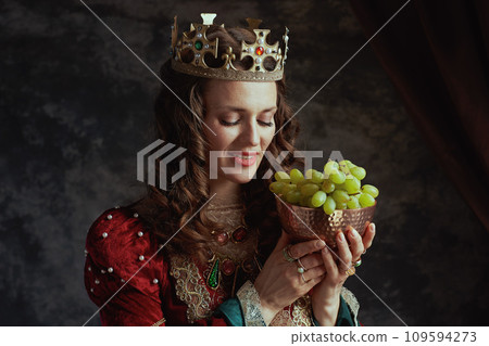 smiling medieval queen in red dress with plate of grapes smiling medieval queen in red dress with plate of grapes 109594273