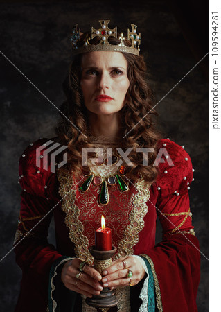 medieval queen in red dress with candle and crown 109594281