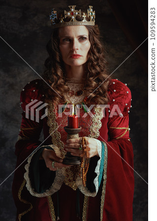 medieval queen in red dress with candle and crown 109594283