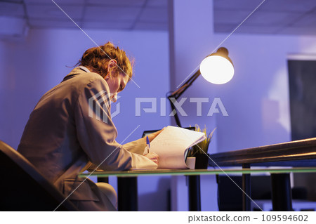 Businesswoman looking at papers with financial growth report while working overtime at investment plan to increase company profit. Executive manager planning marketing strategy. Business concept 109594602