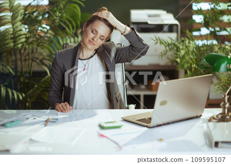 smiling modern business woman at work stretching neck 109595107