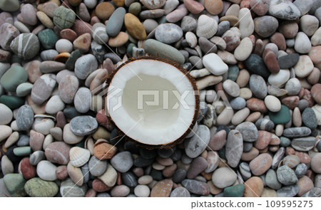 Half Coconut On A Colored Sea Stones Texture Background Half Coconut On A Colored Sea Stones Texture Background 109595275
