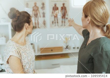 Seen from behind female massage therapist in massage cabinet 109595414