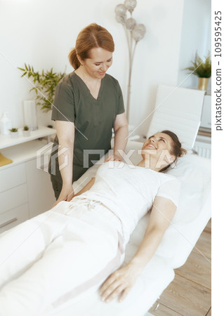 happy massage therapist woman in massage cabinet doing checkup 109595425