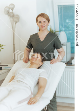 happy massage therapist woman in massage cabinet with client 109595427
