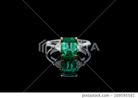 beautiful ring made of gold with precious stones emerald and diamonds on a black background beautiful ring made of gold with precious stones emerald and diamonds on a black background 109595581