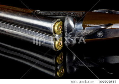 Vintage Side by Side Shotgun with Cartridges on a Reflective Black Surface 109595641