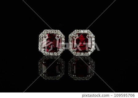 beautiful garnet earrings with diamonds in a gold chain on a black background beautiful garnet earrings with diamonds in a gold chain on a black background 109595706