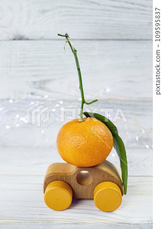 Christmas, toy car with tangerine on the roof, on a white wooden background, concept for Christmas shopping, home delivery Christmas, toy car with tangerine on the roof, on a white wooden background, concept for Christmas shopping, home delivery 109595837