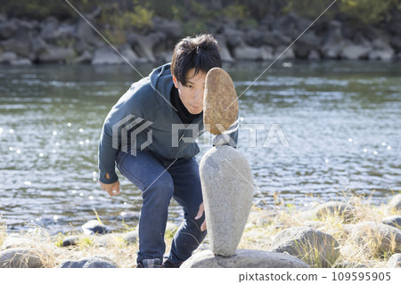 A man checking completed rock balancing A man checking completed rock balancing 109595905