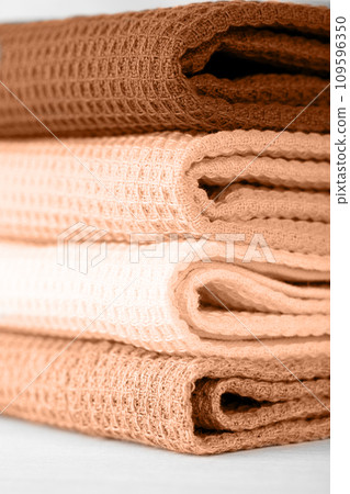 Stack of colorful cotton kitchen towels toned with color of the year 2024 Peach Fuzz Stack of colorful cotton kitchen towels toned with color of the year 2024 Peach Fuzz 109596350