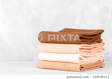 Stack of colorful cotton kitchen towels toned with color of the year 2024 Peach Fuzz Stack of colorful cotton kitchen towels toned with color of the year 2024 Peach Fuzz 109596351