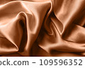Texture of silk fabric toned with color of the year 2024 peach fuzz, close up 109596352