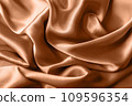 Texture of silk fabric toned with color of the year 2024 peach fuzz, close up 109596354