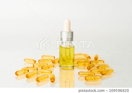 Oil capsules and serum bottle with dropper on white background. Nutritional supplement contains fish oil, omega 3, omega 6, omega 9, vitamin e, vitamin d and vitamin. Health care and beauty concept. Oil capsules and serum bottle with dropper on white background. Nutritional supplement contains fish oil, omega 3, omega 6, omega 9, vitamin e, vitamin d and vitamin. Health care and beauty concept. 109596820